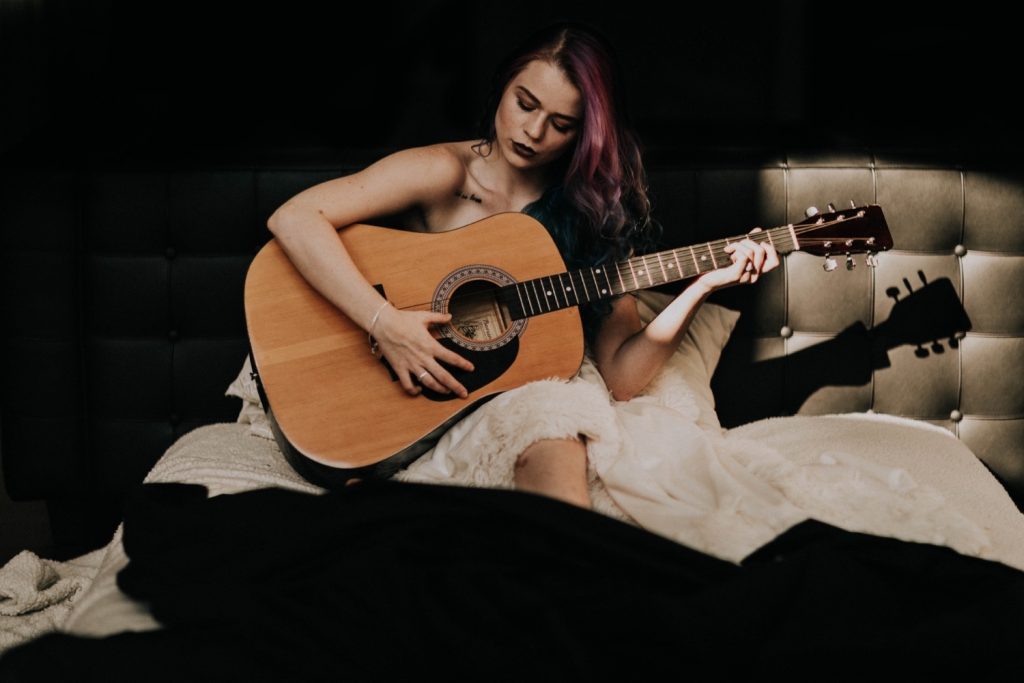 woman playing guitar during her dark and moody boudoir session