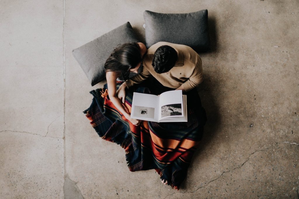 engaged couple reading and snuggling up with each other during their at-home engagement photos