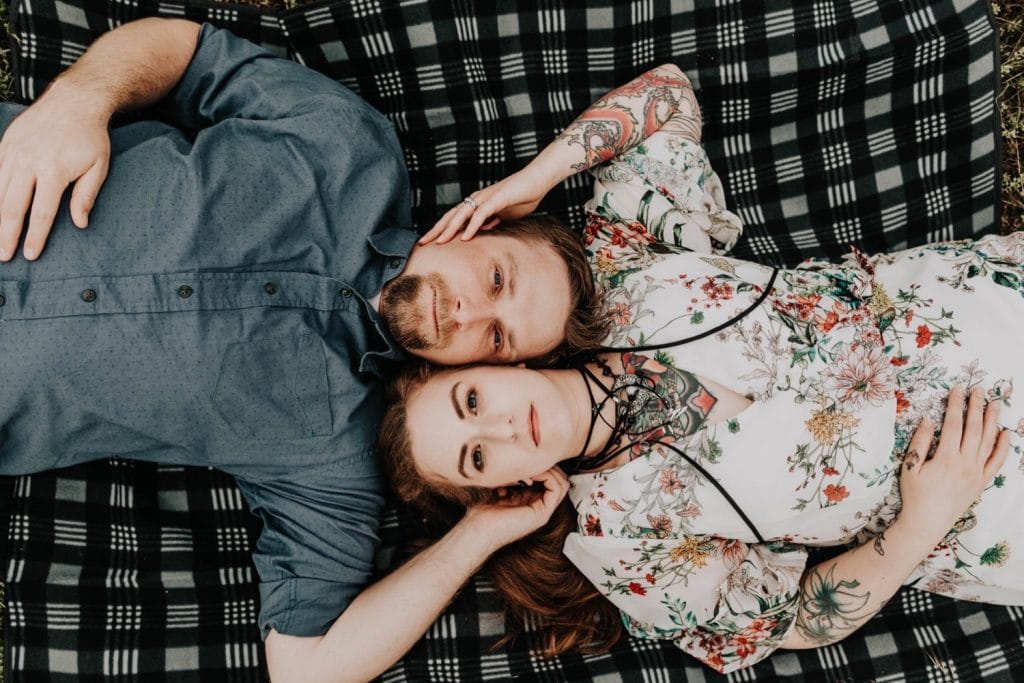 couple laying on a blanket and looking up at the camera