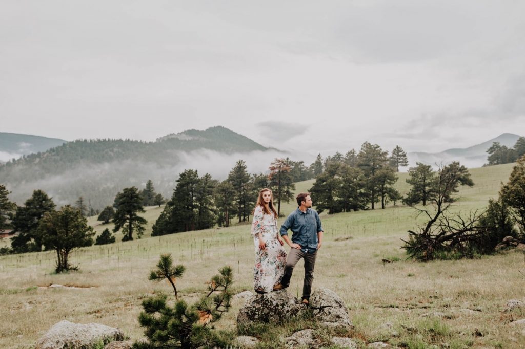 engaged couple wandering through an open field near Boulder Colorado
