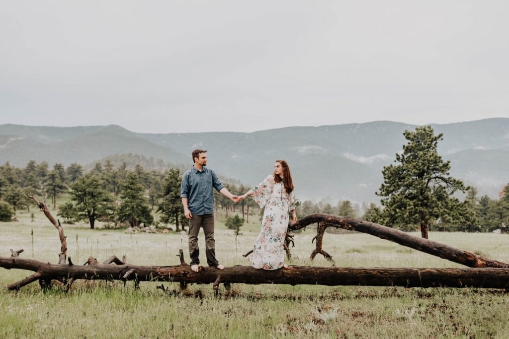 Boulder engagement photos taken on a fallen tree trunk in the mountains