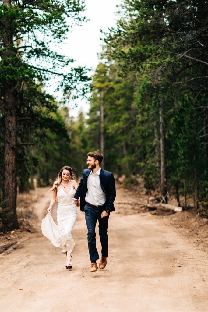 couple running down a dirt road during their camper van elopement wedding in the Colorado Rocky Mountains