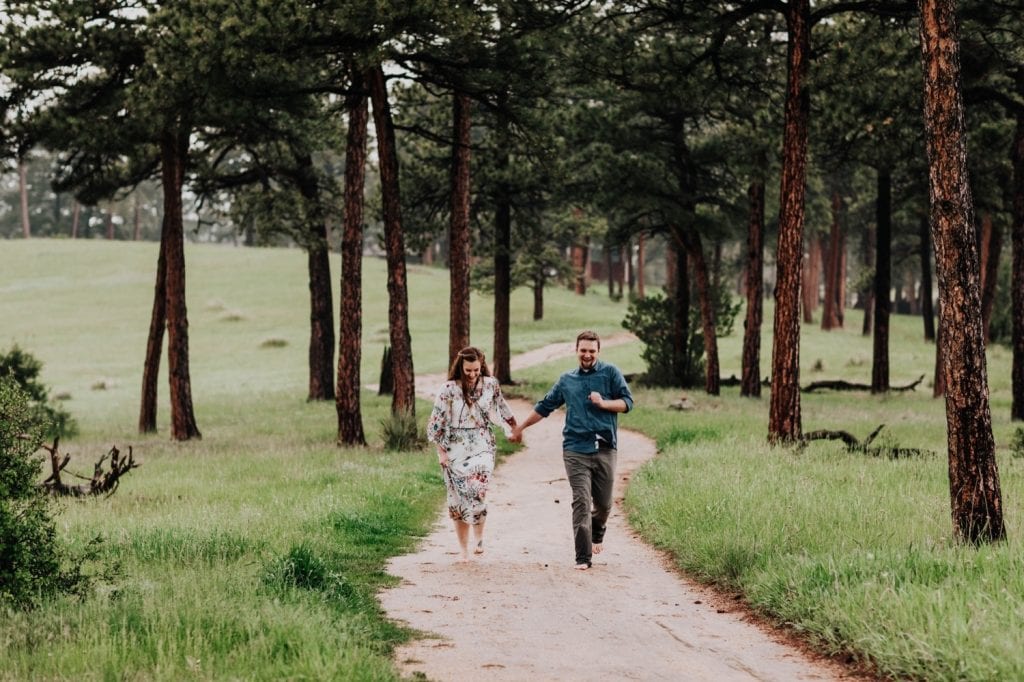 engaged couple running down a hiking trail in Boulder together