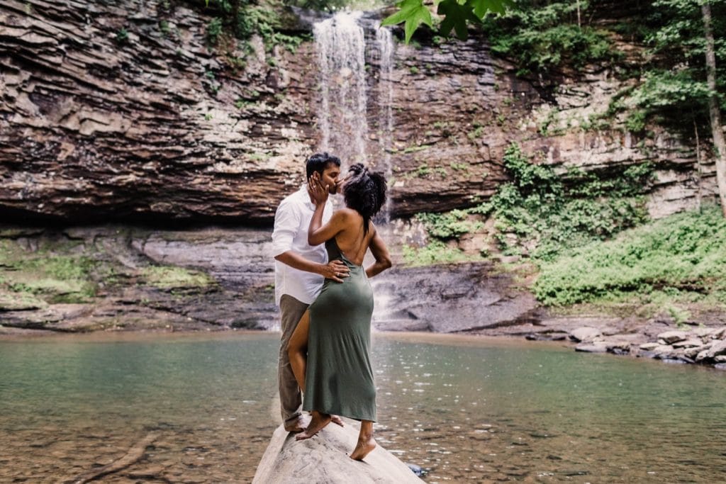 engaged couple admiring a giant waterfall during their waterfall engagement session