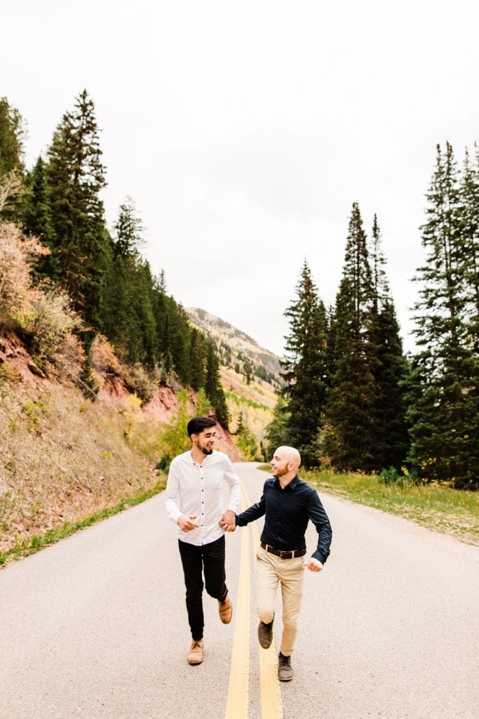 newly engaged same sex couple running through the mountains in Aspen Colorado after their Maroon Bells proposal
