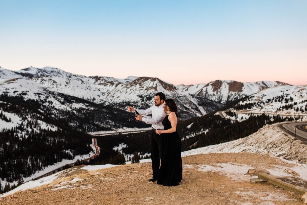 engaged couple popping champagne during their snowy Colorado winter engagement session