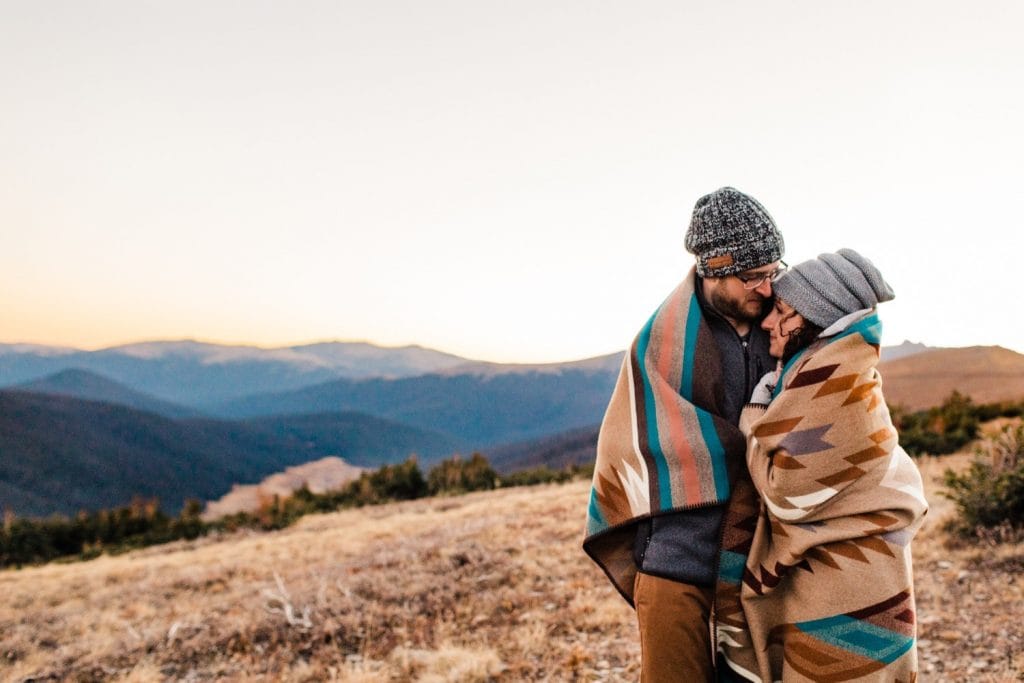 engaged couple curled up in a Pendleton blanket during their Colorado Rocky Mountain National Park engagement session | Rocky Mountain elopement photographers