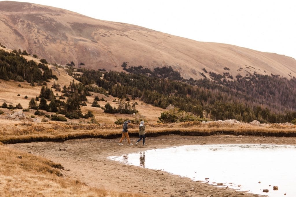 couple hiking around an alpine lake in the Rocky Mountains during their engagement session | Rocky Mountain elopement photographers