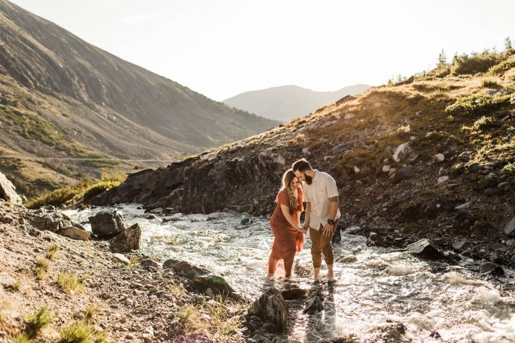 eloping couple walking into a mountain creek during their Breckenridge elopement style adventure session | Colorado elopement photographers in Breckenridge
