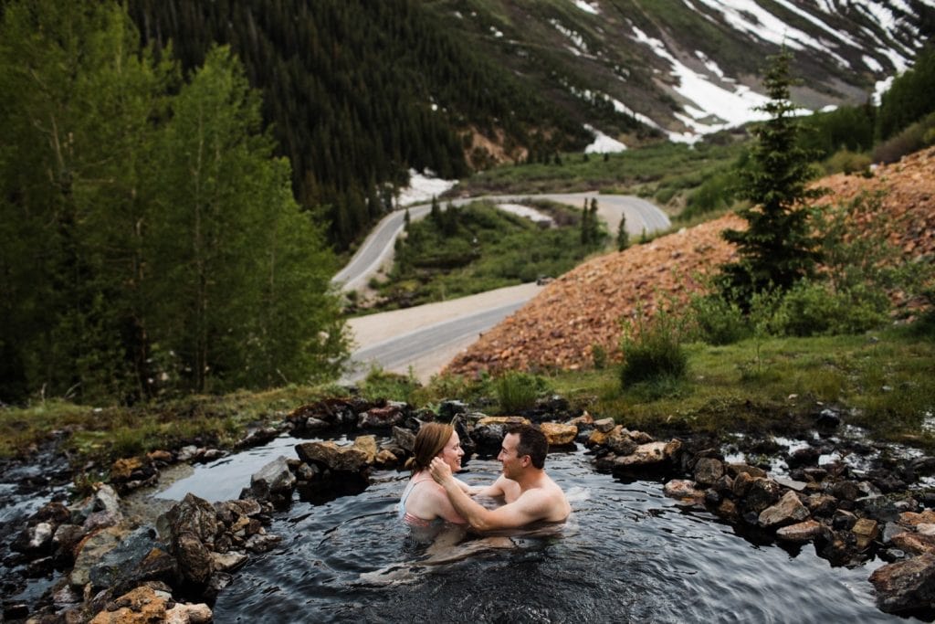 couple hanging out in a mountain hot spring during their Telluride engagement photos in Colorado