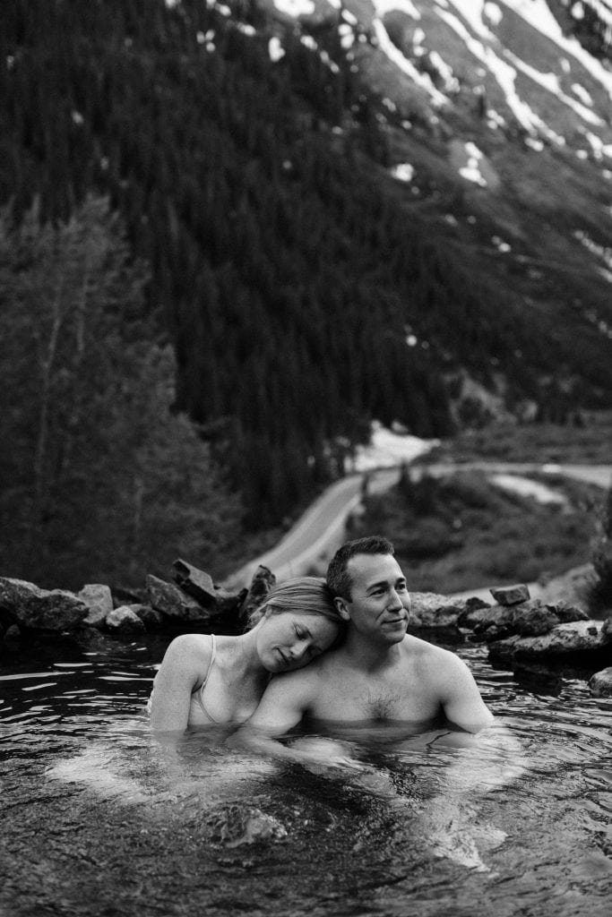 couple enjoying a secret hot spring in Telluride Colorado while they get their engagement photos taken