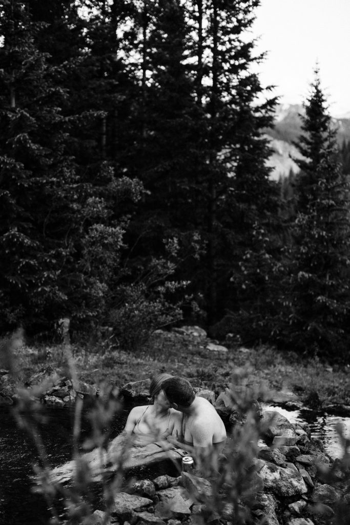 adventurous Colorado couple enjoying the sunset in the San Juan Mountains during their secret hot springs engagement session in Telluride Colorado