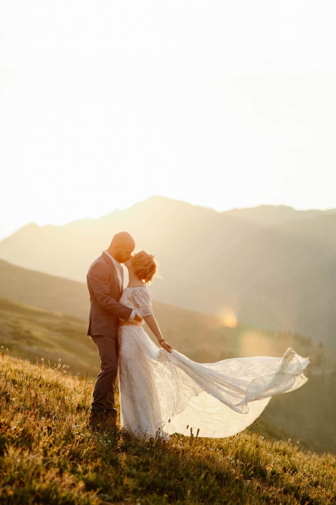 eloping couple kissing during golden hour as the bride tosses her dress behind her - planning elopement checklist