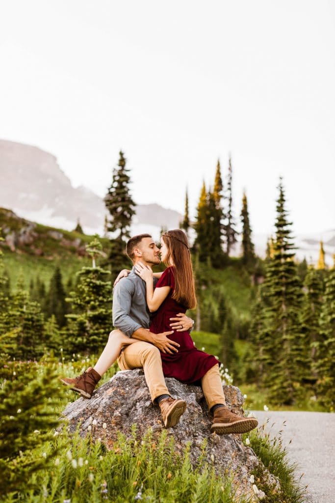 couple kissing on a rock in the middle of a wildflower field during their engagement photos in Seattle WA
