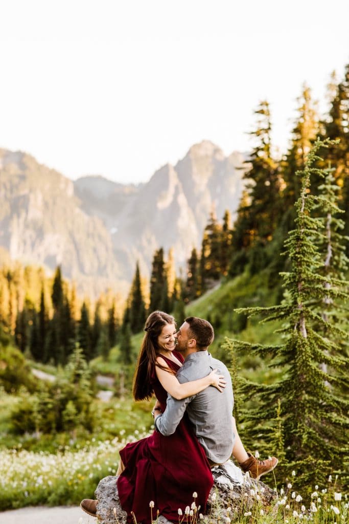 couple kissing on a rock in the middle of a wildflower field during their engagement photos in Seattle