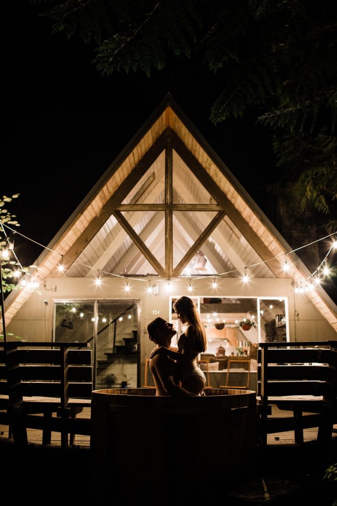 engagement photos in Seattle WA of a couple in their a-frame cabin hot tub at night