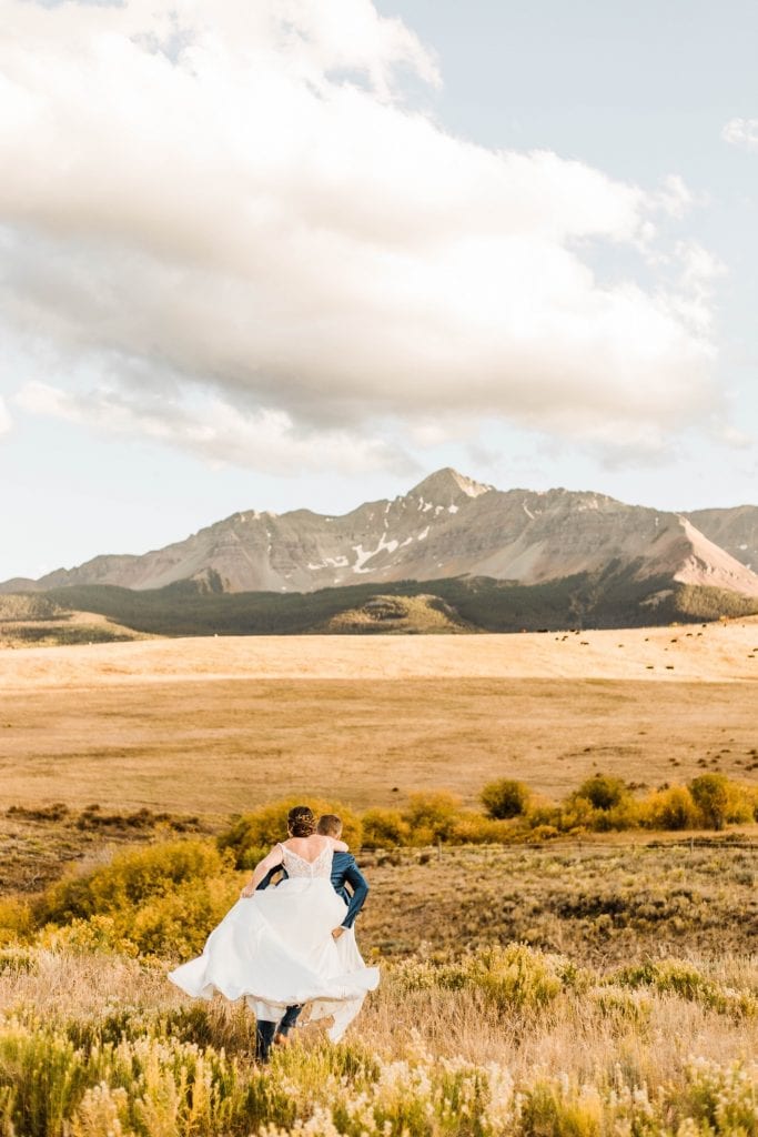 married couple running through the mountains during their Telluride wedding sunset photos | image by Telluride wedding photographers