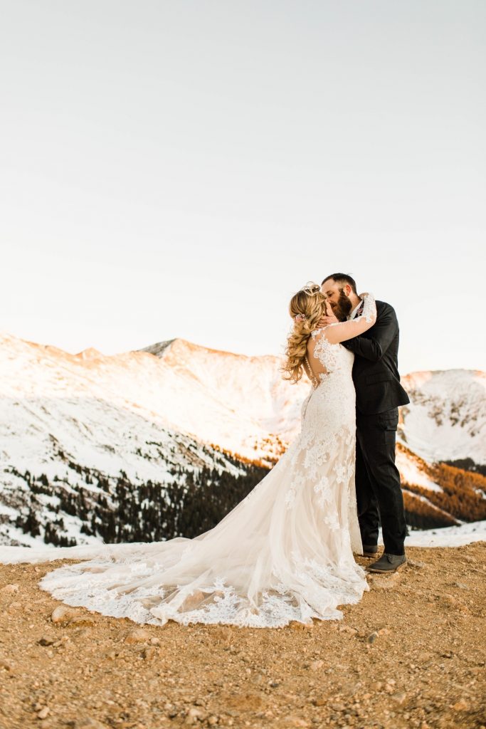 newly married couple kissing on a hiking trail through the Rocky Mountains at sunset after their Sapphire Point Overlook wedding