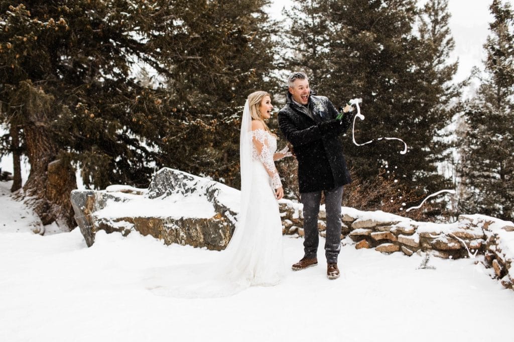 eloping couple popping champagne for their snowy winter Sapphire Point elopement