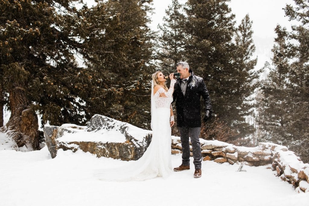 bride drinking champagne to celebrate her winter Sapphire Point elopement in the snow