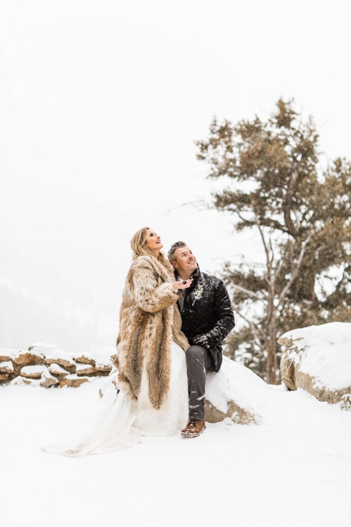 eloping couple watching snow fall during their Sapphire Point elopement in the winter