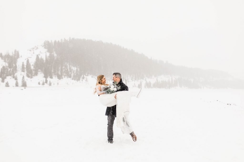 groom lifting and spinning bride around in celebration after their Sapphire Point elopement in the winter