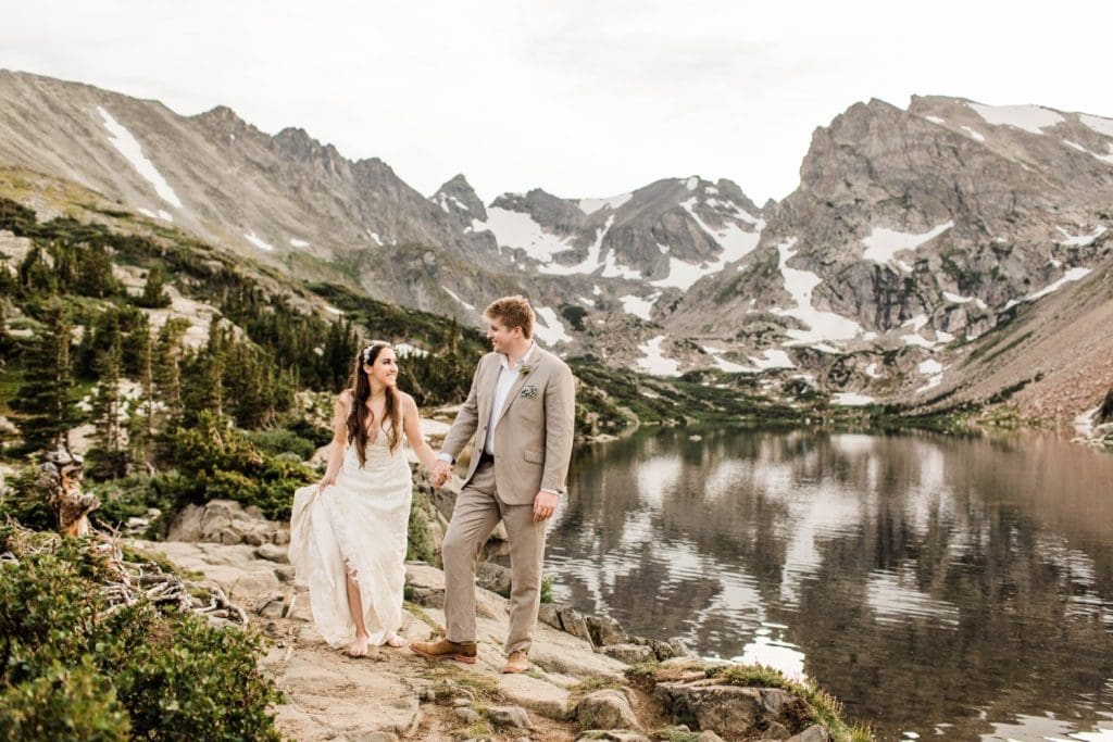 married couple hiking next to an alpine lake during their mountain wedding in Colorado