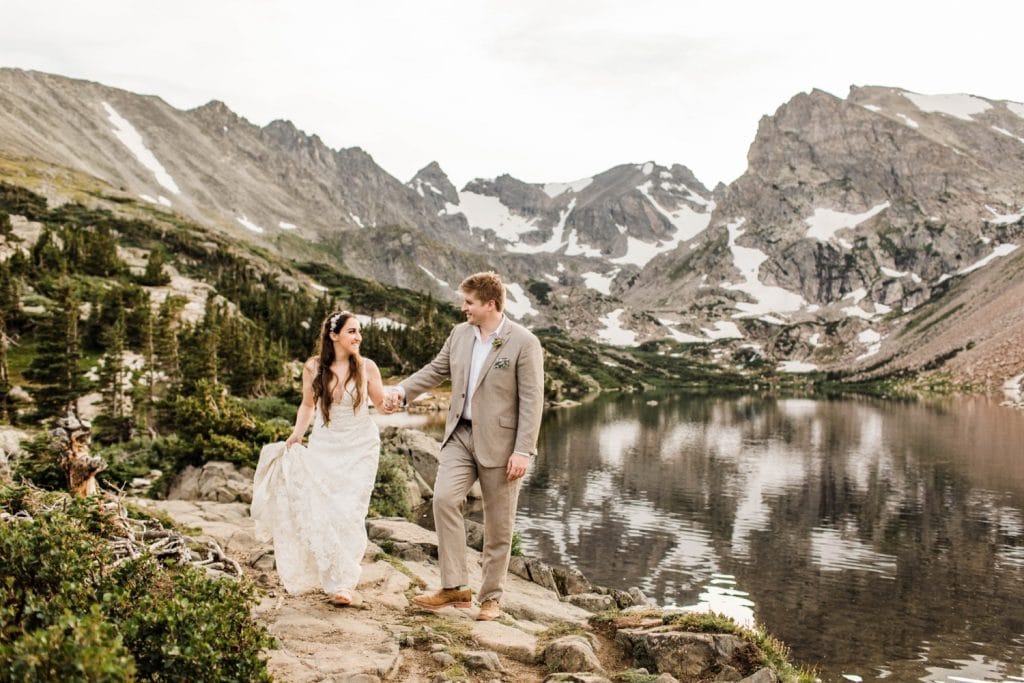 married couple hiking next to an alpine lake during their mountain wedding in Colorado