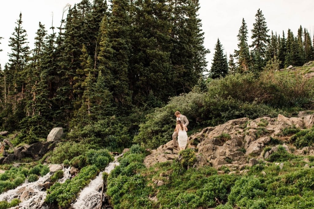 mountain wedding in Colorado where a couple hikes past a waterfall in the high country