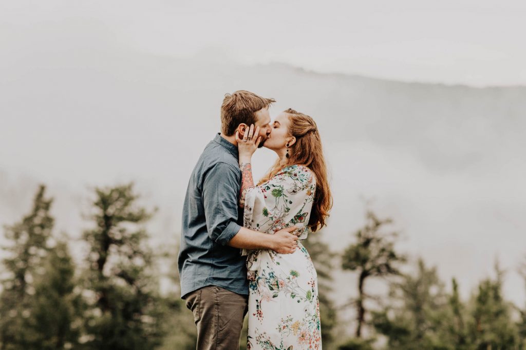 image of a couple kissing on a foggy day in the Rocky Mountains taken by a Colorado engagement photographer