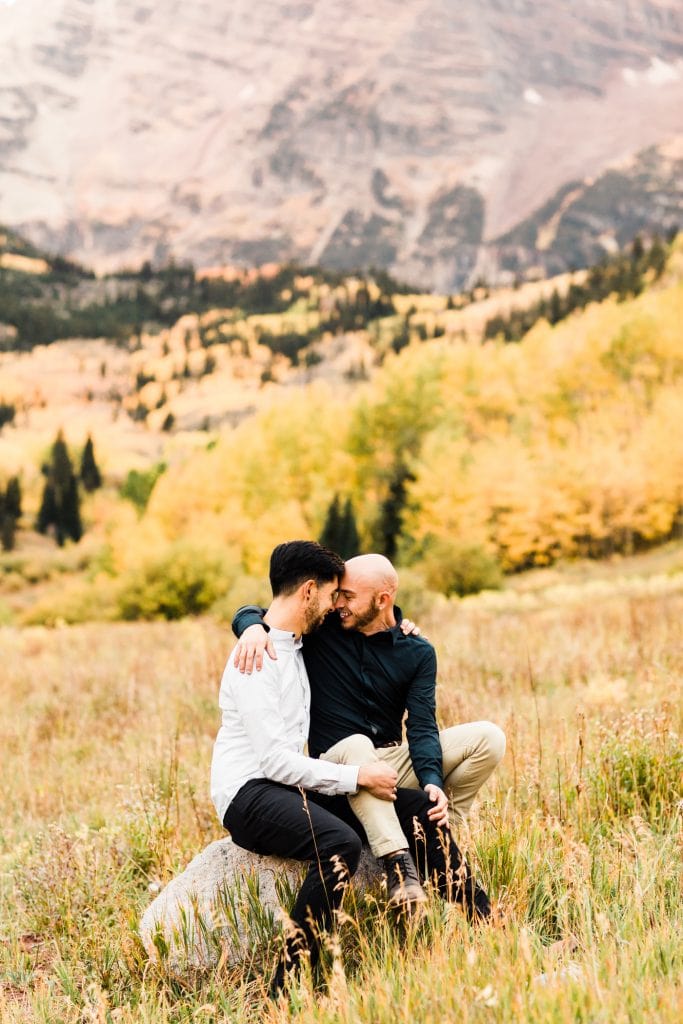 engaged couple sitting on a rock together in the mountains