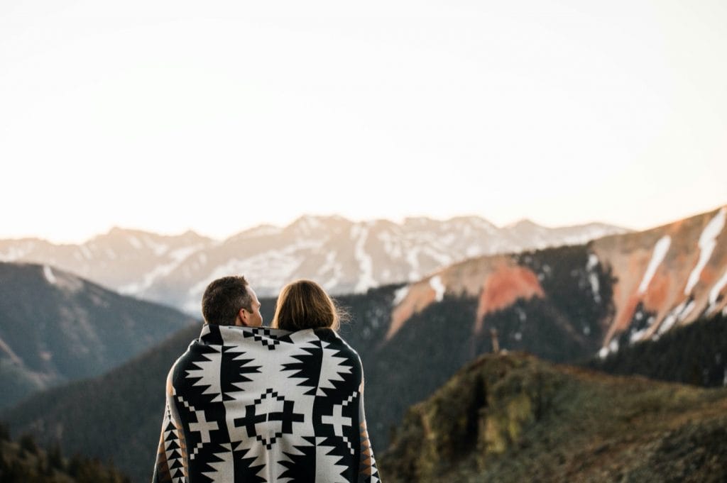 Telluride elopement couple wrapped up in a blanket while watching the sun rise in the mountains