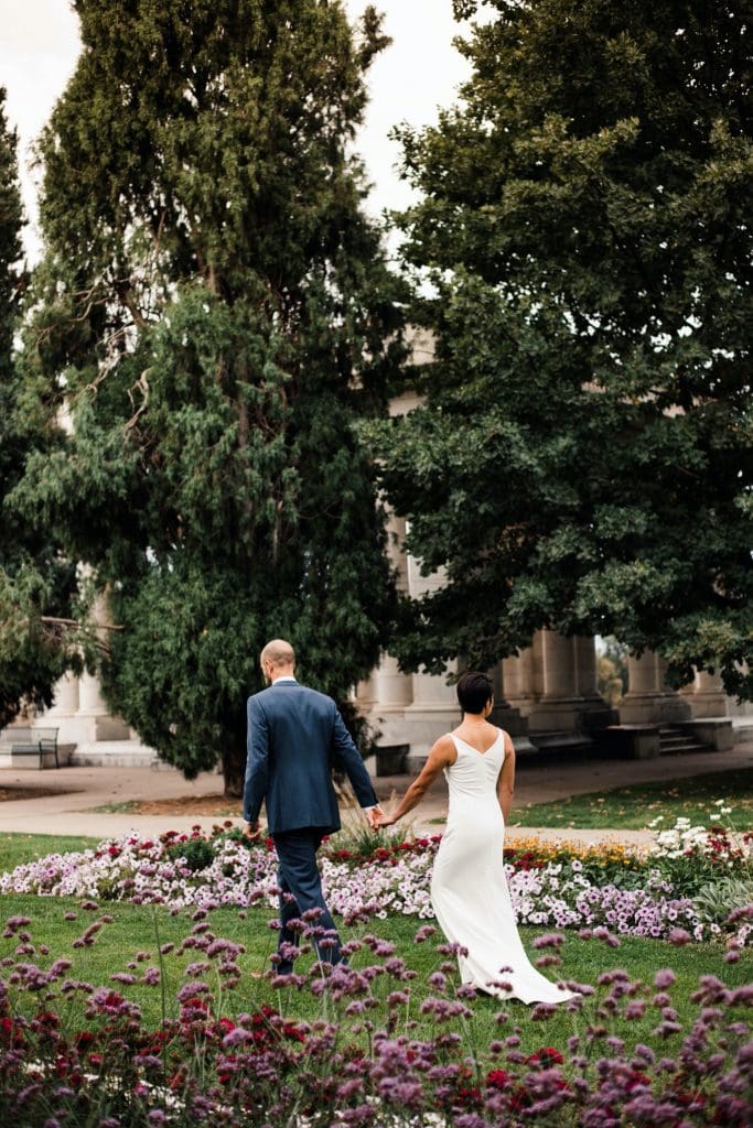 couple walking through a garden before their Denver Botanic Gardens wedding