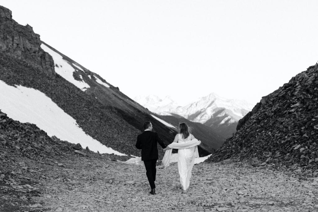 eloping couple running down a mountain pass outside of Telluride Colorado