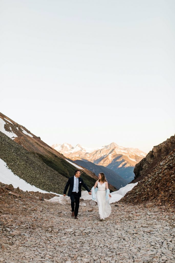 eloping couple running down a mountain pass outside of Telluride Colorado