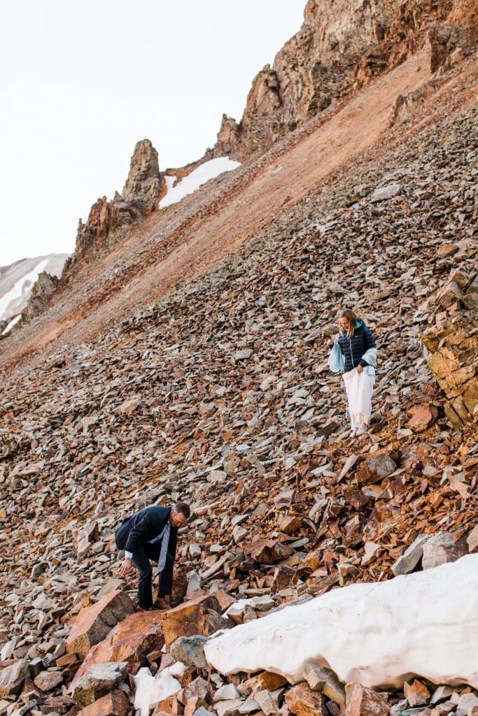 eloping couple scrambling down a rocky mountainside after saying their vows outside of Telluride