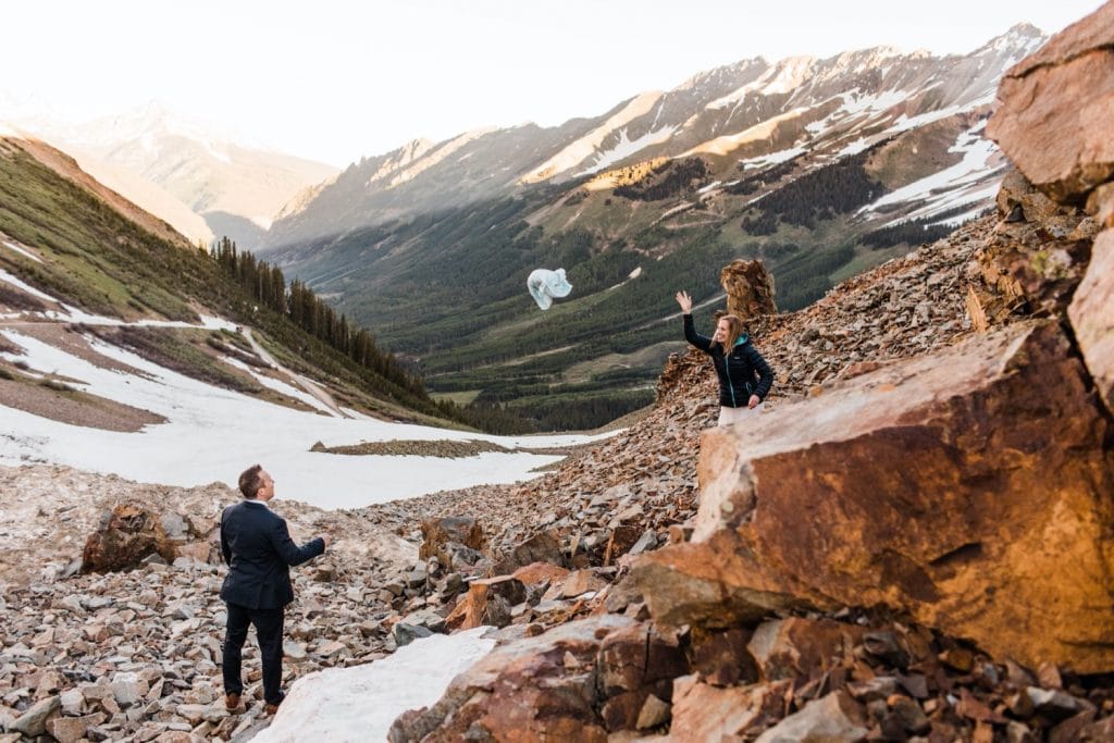 eloping couple scrambling down a rocky mountainside after saying their vows outside of Telluride