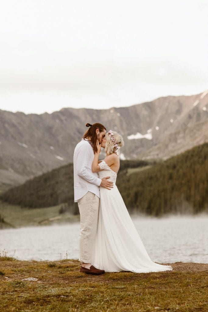 couple admiring a steaming alpine lake before they begin their lake wedding ceremony at sunrise