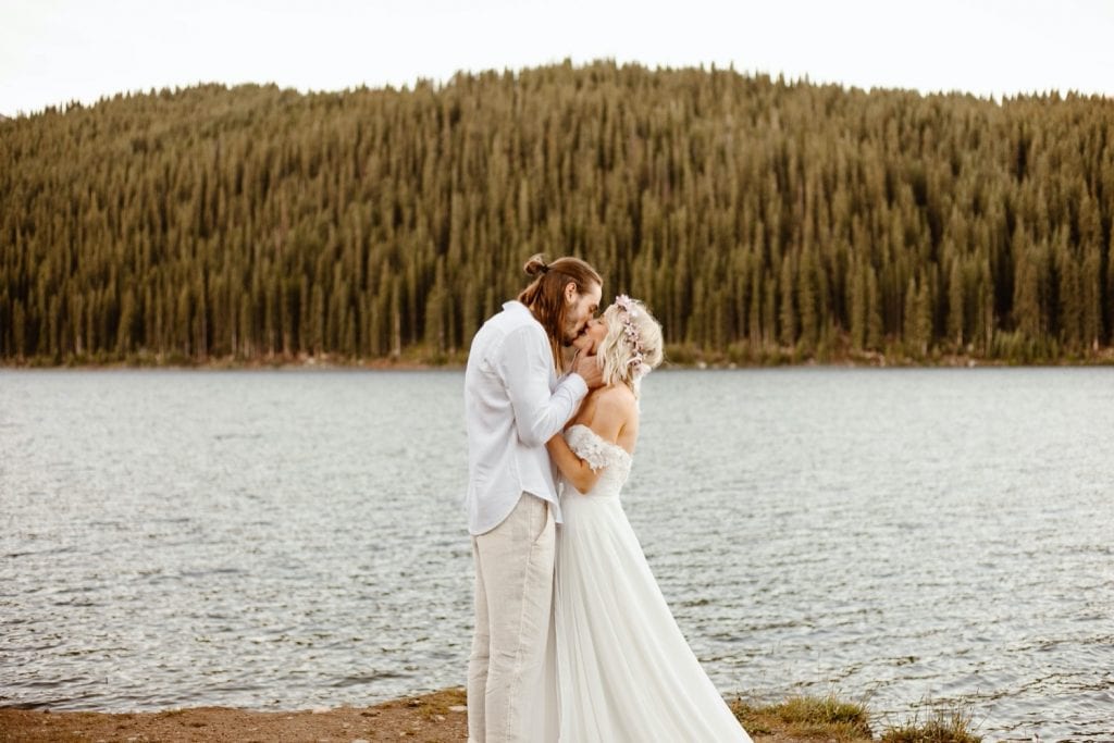 couple having their first kiss during their lake wedding ceremony in Colorado