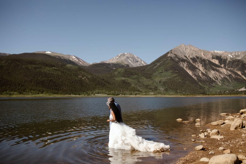 couple getting into a lake in their wedding attire after they eloped in Aspen Colorado