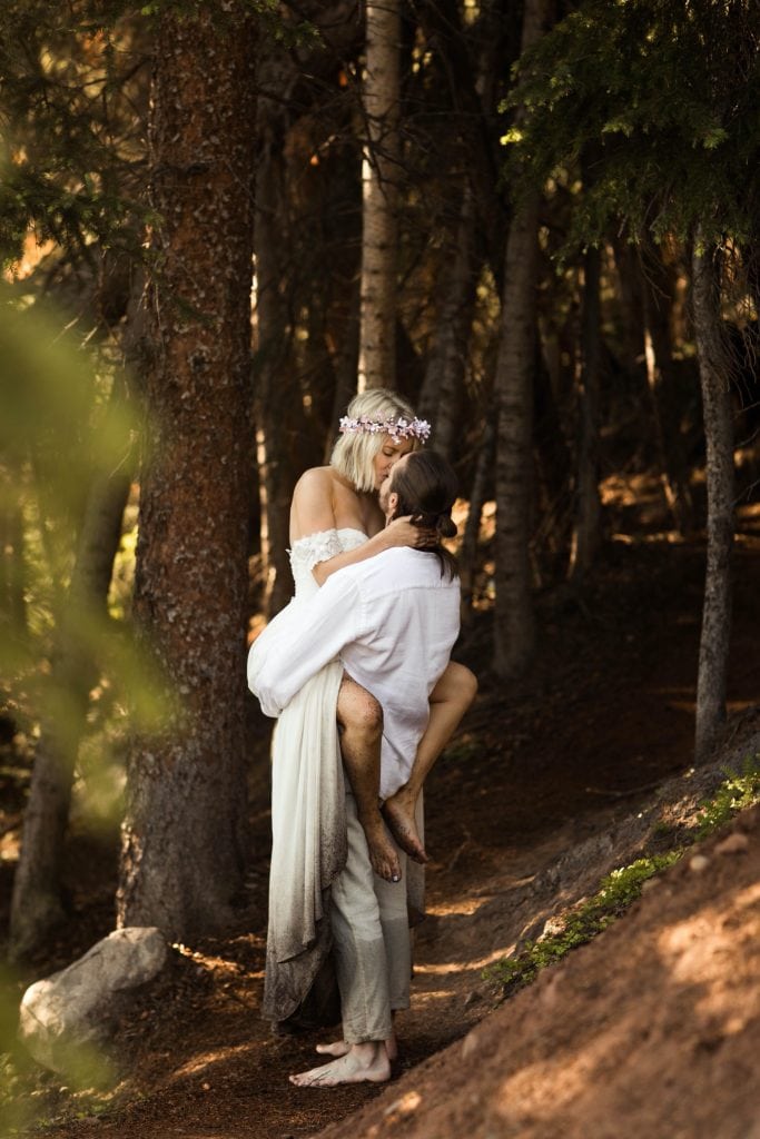 groom lifting the bride for a kiss in the forest after their elopement wedding