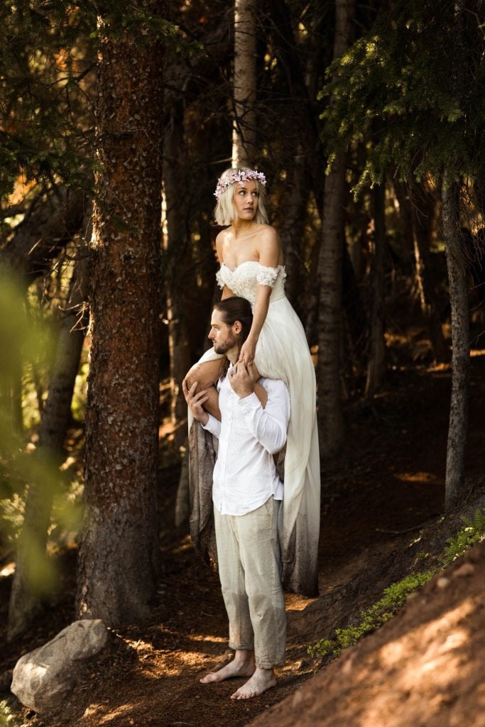 bride sitting on groom's shoulder while hiking in the forest after their elopement ceremony