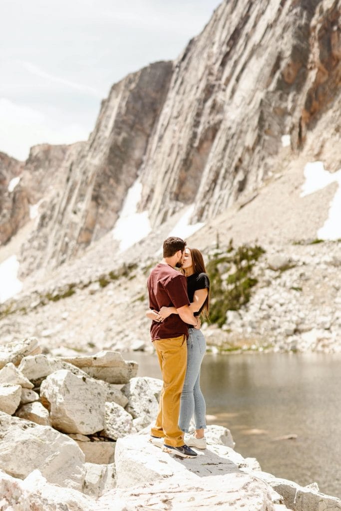 couple kissing on a mountaintop during their engagement