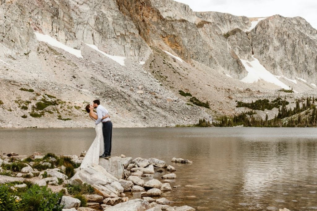 eloping couple kissing by a lake in the Snowy Range Mountains of Wyoming