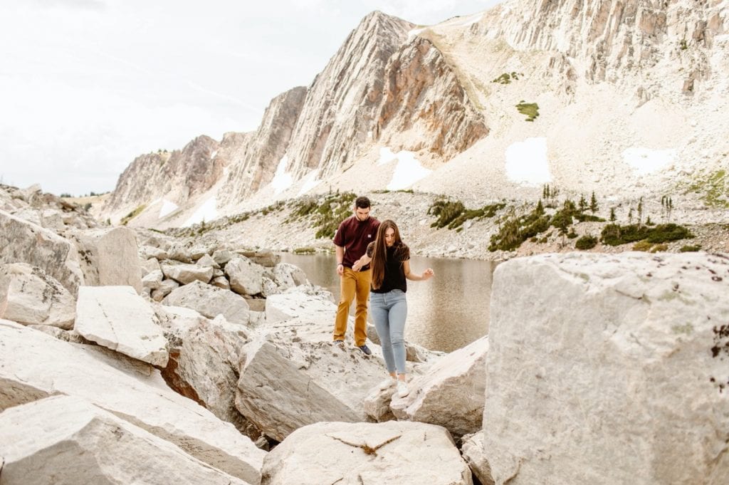 couple hiking through a boulder field while having their mountain engagement photos taken in Wyoming