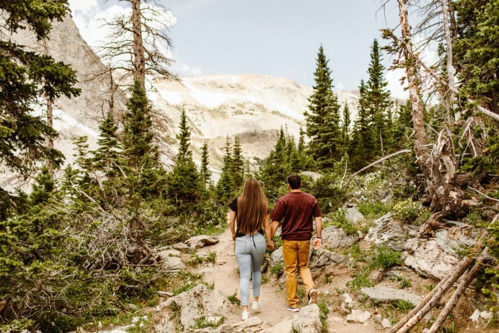 couple hiking up the trail for their mountain engagement photos