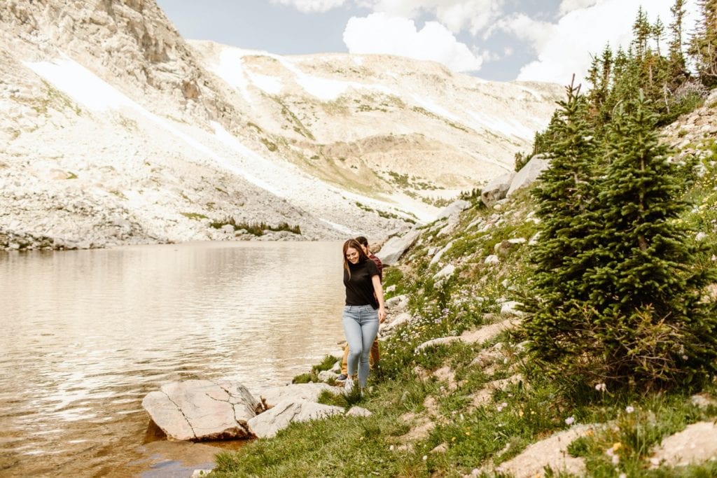 mountain engagement photos of a couple hiking by an alpine lake