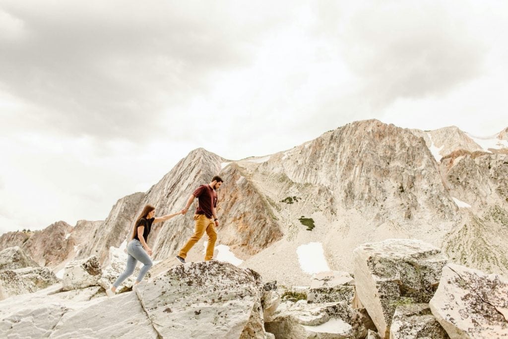 man leading woman up a mountain during their mountain engagement photos
