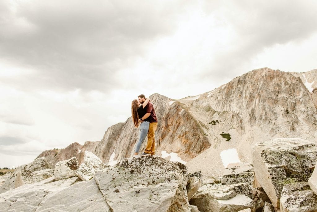engaged couple kissing on a mountaintop in Wyoming