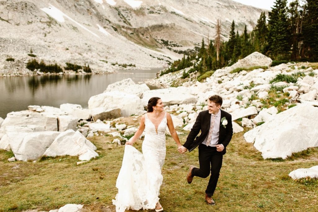 bride and groom running together in the mountains